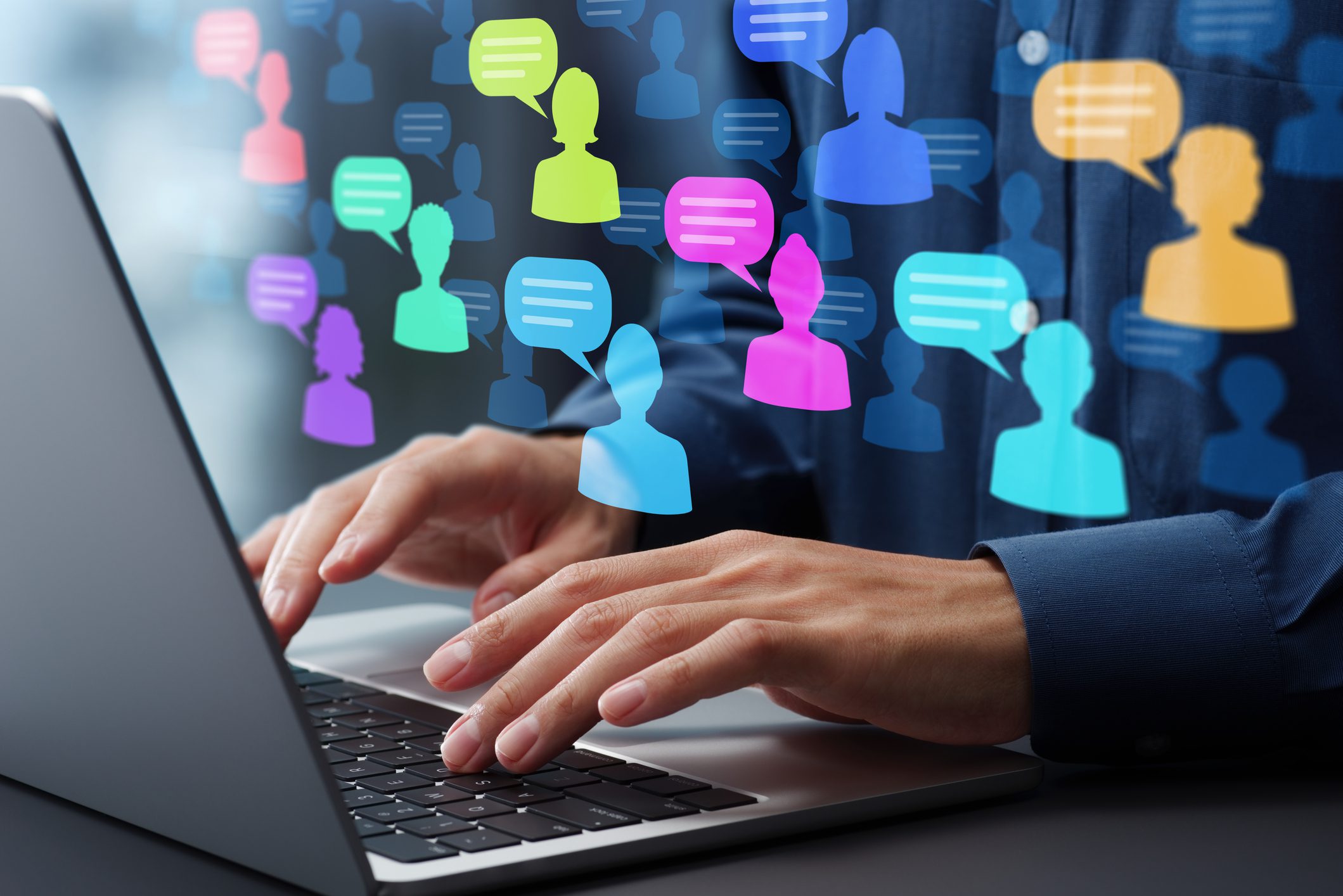 Hands typing on a laptop with colorful digital chat bubbles above.