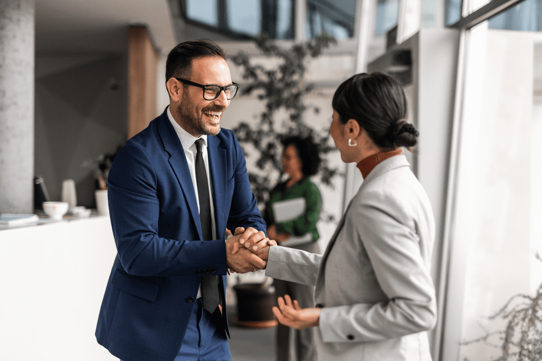 Man and woman shaking hands in office.