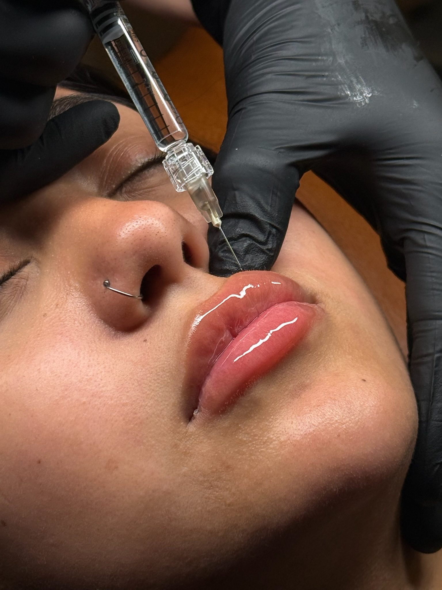 Close-up of lip tattooing procedure with gloved hands.