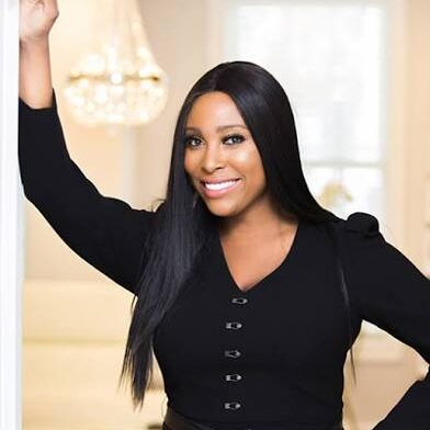 Confident woman in a black top smiling indoors.